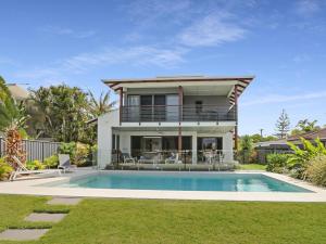 a house with a swimming pool in front of a house at WATERFRONT HOME BORDERING MOOLOOLABA in Buddina