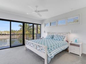 a bedroom with a bed and a balcony at WATERFRONT HOME BORDERING MOOLOOLABA in Buddina