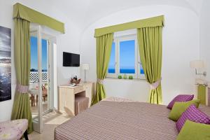 a bedroom with a bed and a tv and windows at Capri Wine Hotel in Capri