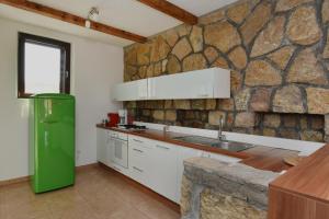 a kitchen with a green refrigerator and a stone wall at Villa Ariel - Pool, Beach & Basketball court in Luštica