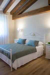 1 dormitorio con 1 cama blanca grande con almohadas azules en Gigante Wine & Welcome, en Corno di Rosazzo