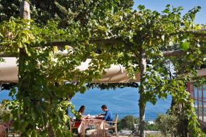 a group of people sitting at a table under a tree at Capri Wine Hotel in Capri