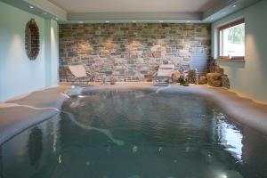 a large swimming pool in a room with two chairs at Gigante Wine & Welcome in Corno di Rosazzo