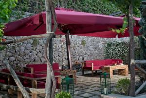 a patio with red chairs and a large umbrella at Capri Wine Hotel in Capri