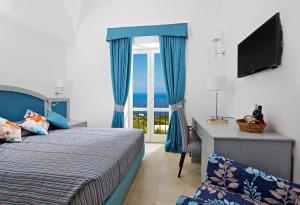 a bedroom with a bed and a desk and a window at Capri Wine Hotel in Capri