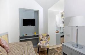 a bedroom with a bed and a chair and a television at Capri Wine Hotel in Capri
