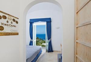 a bedroom with a bed and a window with the ocean at Capri Wine Hotel in Capri
