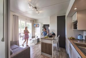 Dos mujeres de pie en una cocina en un pequeño apartamento en Camping Kaul, en Wiltz