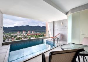 balcón con piscina, mesa y sillas en Lexis Suites Penang en Bayan Lepas