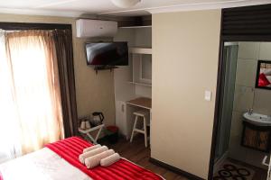 een slaapkamer met een bed met een rode deken bij African Adventures Accommodation in Joostenberg Vlakte