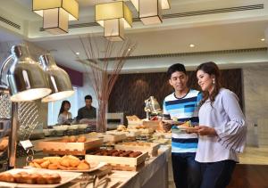 a man and a woman standing in front of a buffet at Lexis Suites Penang in Bayan Lepas