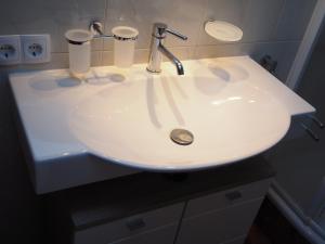 Un lavabo blanco en un baño con dos tazas. en Haus Gabriel, en Fliess