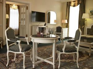 ein Wohnzimmer mit einem Tisch, Stühlen und einem TV in der Unterkunft Esplanade Spa and Golf Resort in Marienbad