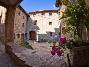 a stone building with a courtyard with pink flowers at Casa Massa in Baro