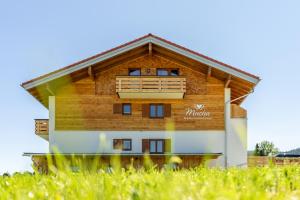 ein Holzgebäude mit einem Balkon auf einem Rasenplatz in der Unterkunft Berghaus Mucha - NATURPARK NAGELFLUHKETTE - Bergbahn im Sommer gratis in Bolsterlang