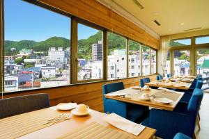a restaurant with wooden tables and blue chairs and windows at Villa Concordia Resort & Spa in Hakodate