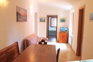 Una sala de estar con una mesa, un sofá y un televisor. en La Dimora nel Parco - ArgonautiVacanze, en Rio Marina