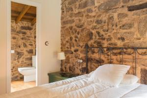 a bed in a room with a stone wall at Villa Valedoso in Cabañas