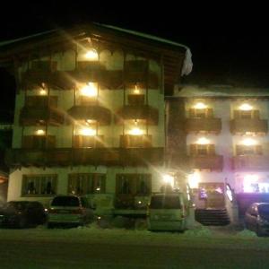 um edifício com carros estacionados em frente a ele à noite em Hotel Sole em Passo del Tonale