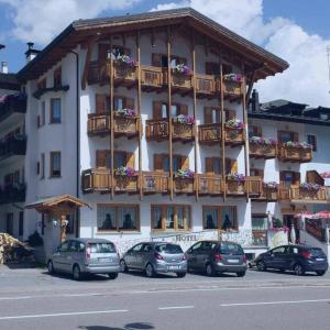 a large building with cars parked in front of it at Hotel Sole in Passo del Tonale