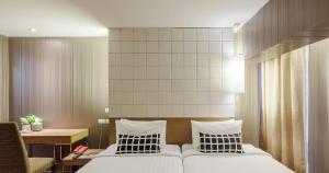 a bedroom with two beds and a table and a desk at Tango Vibrant Living Hotel - SHA Extra Plus in Bangkok