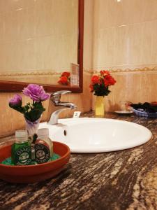 a bathroom counter with a sink and flowers on it at Oasey Ayurveda Hotel in Bentota