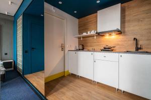 a kitchen with white cabinets and a blue door at Greenfeel Hotel Pskov in Pskov