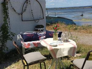 a table with a vase of flowers on it next to the water at Cabanon de pêcheur en bord de lagune in Sète