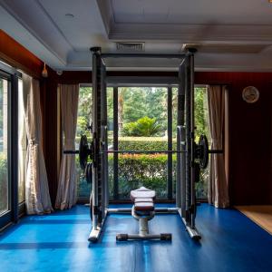 a gym with a bench press in front of a window at Hangzhou Rose Garden Resort & Spa in Hangzhou
