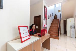 une femme assise au comptoir avec un ordinateur portable dans l'établissement RedDoorz @ Pengayoman Panakkukang 3, à Makassar