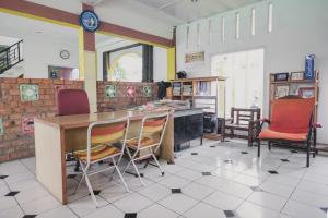 eine Küche mit Stühlen, einem Tisch und einer Uhr in der Unterkunft RedDoorz Syariah @ Pasir Putih Jambi in Jambi