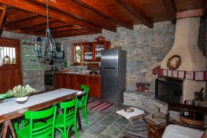 Il comprend une cuisine équipée d'un réfrigérateur et d'une table avec des chaises vertes. dans l'établissement Oceanis cottage house, à Órmos Koumaíïkon