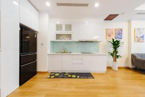 een keuken met witte kasten en een zwarte koelkast bij MARCH HOUSE - Park Premium TimesCity - 2-3 Bedrooms in Hanoi