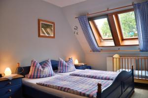 ein Schlafzimmer mit einem Bett, zwei Fenstern und einem Kinderbett in der Unterkunft Ferienwohnung Fegebank in Grethem