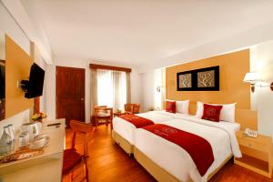 a hotel room with a large bed and a television at Puri Saron Hotel Baruna Beach Lovina in Lovina