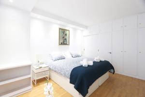 a white bedroom with a bed with a blue blanket at Urbantec Realty - Plaza de Colón in Madrid