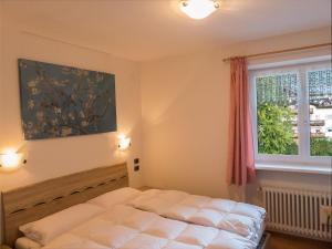 a bedroom with a white bed and a window at Casa Soraruf in Campitello di Fassa