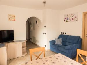 a living room with a blue couch and a tv at Casa Soraruf in Campitello di Fassa