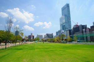 um parque com um campo verde em frente a uma cidade em 遊泊昭和町YupaStay em Osaka