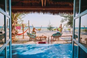 a woman sitting in a chair on the beach at Bamboo Jam in Koh Rong Sanloem