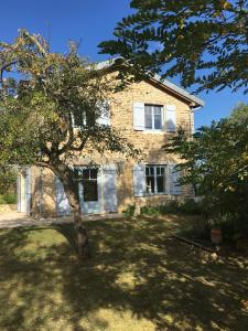 una casa di mattoni con un albero di fronte di Le Fournil des Jardins d'Ayaël a Ozenay