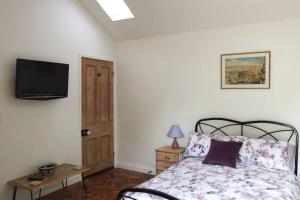 a bedroom with a bed and a tv on the wall at The Piggery at Moorfield Barns in Praze an Beeble