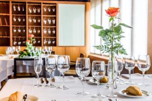 a table with wine glasses and a rose in a vase at Hotel Cala Sant Vicenç - Adults Only in Cala de Sant Vicenc