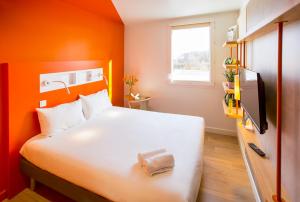 a bedroom with a white bed with an orange wall at Ibis Budget Perigueux Boulazac in Boulazac