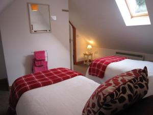 1 dormitorio con 2 camas con sábanas rojas y blancas en Clock House Cottage, en Brook