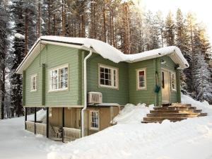 a green house in the snow in the woods at Holiday Home Tuuliranta by Interhome in Nurmes