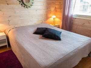 a bedroom with a bed with a black pillow on it at Holiday Home Karitahko a 8 by Interhome in Tahkovuori