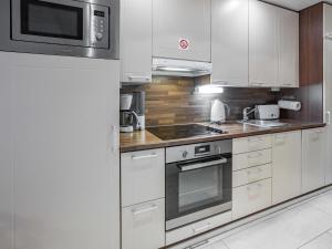 a kitchen with white cabinets and a stove top oven at Holiday Home Yllästar 3 as 616 by Interhome in Äkäslompolo
