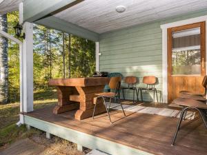 um alpendre com uma mesa de madeira e cadeiras em Holiday Home Heikinniemi by Interhome em Vanaja