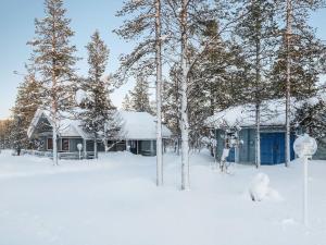 a house covered in snow in front of trees at Holiday Home Keromaja by Interhome in Kakslauttanen
